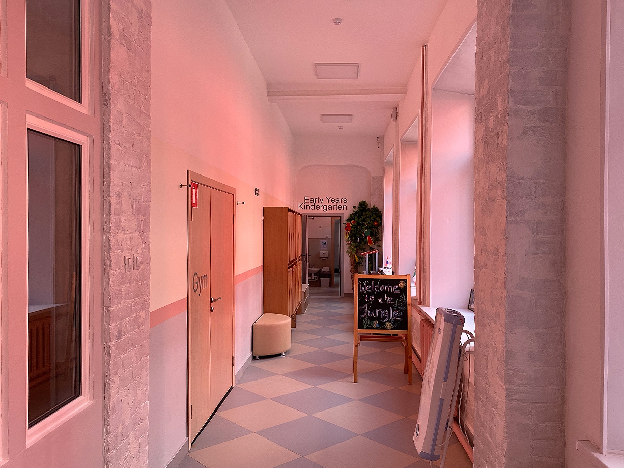 В солнечный день коридоры школы заливает розовый свет — отражение фасада